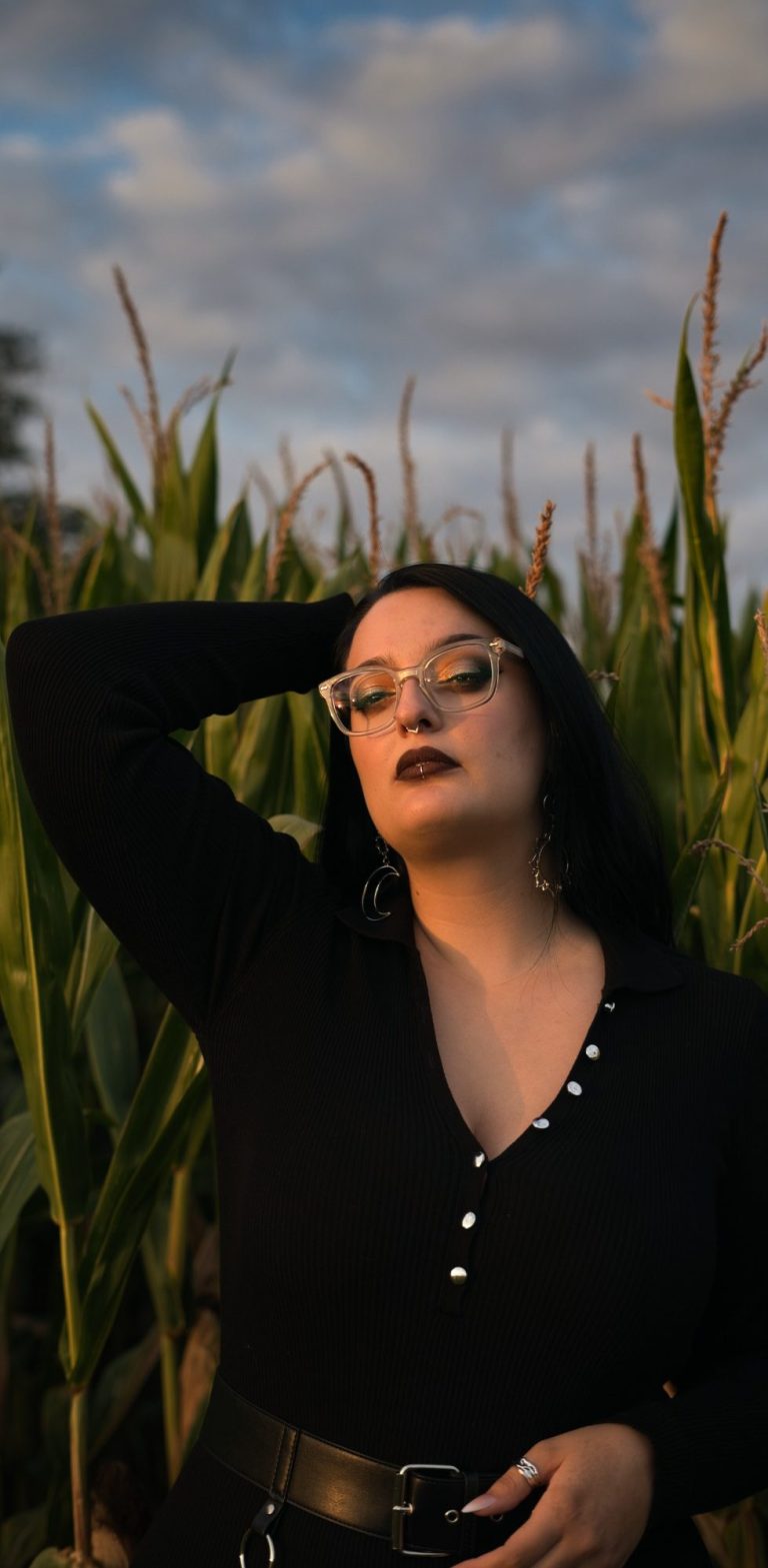 Frau mit langen Haaren in einem schwarzen Oberteil, nachdenklicher Blick in der Natur.