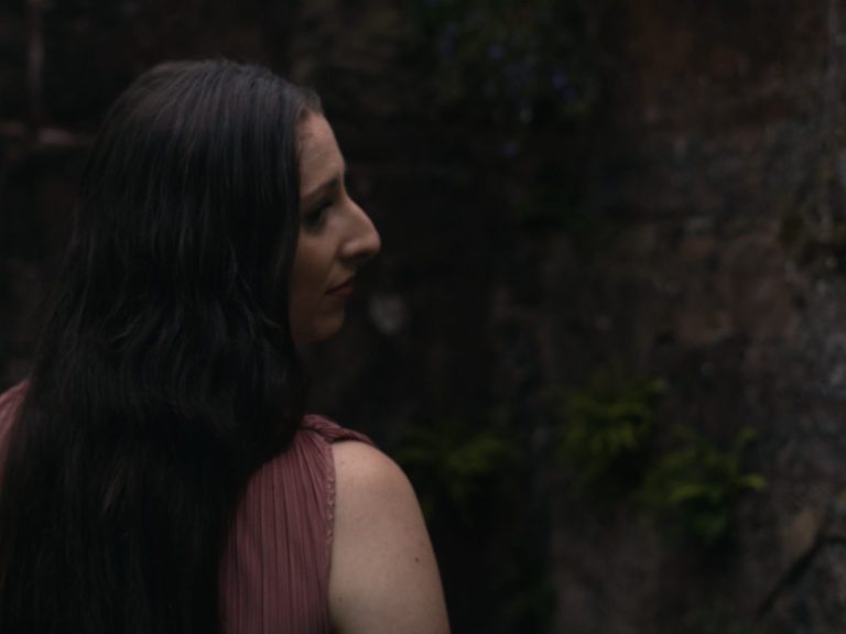 Frau streichelt zarte, rosa Magnolienblüten in einer blühenden Landschaft.