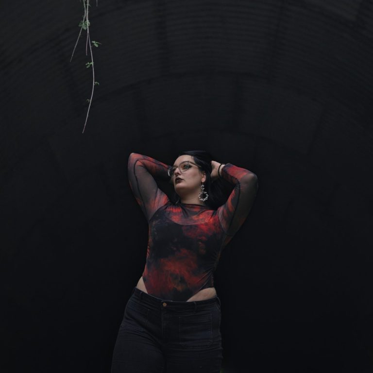 Frau in schwarzem Kleid, umgeben von blühenden Kirschbäumen.